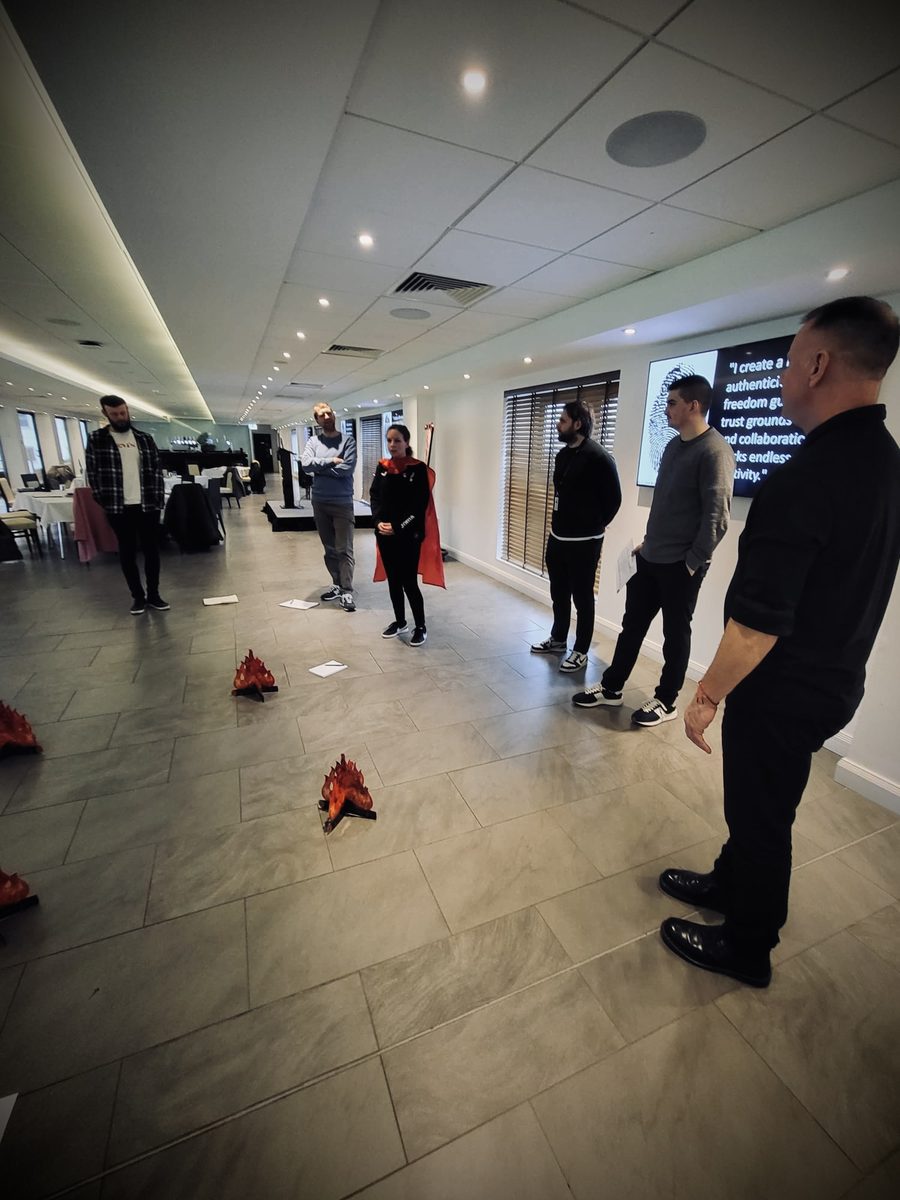 A small group standing in a circle around paper flame cut-outs on the floor during a workshop exercise