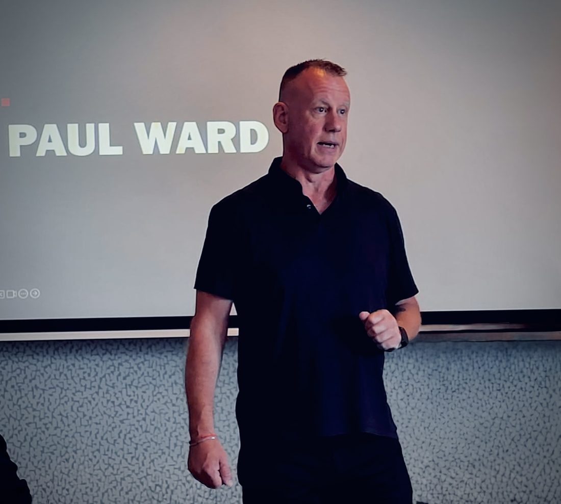 Paul Ward speaking in front of a projected slide with his name on it